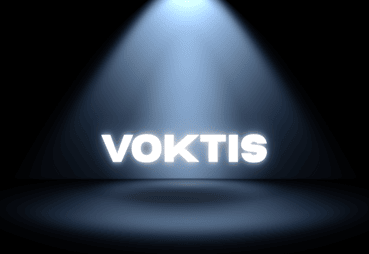 The word VOKTIS in glowing white letters under a spotlight on a dark background.